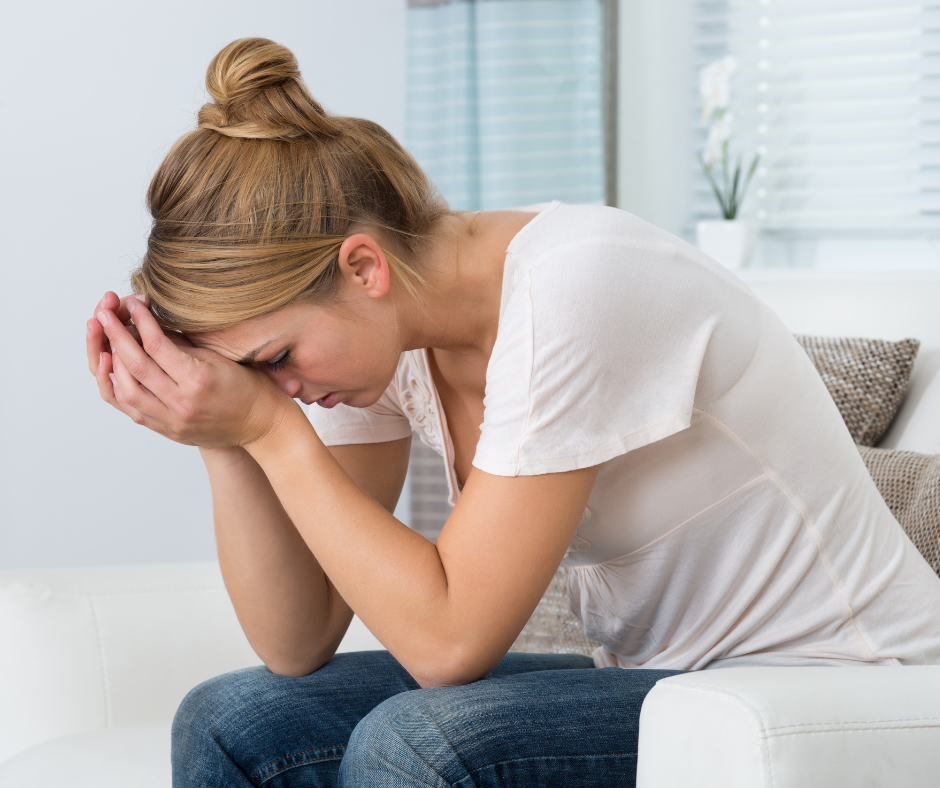 Young stressed woman sitting in living room at home