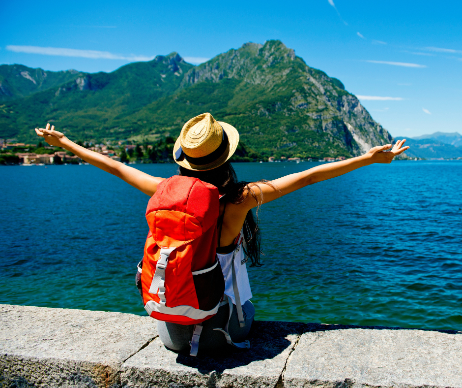 Female traveller sitting on wall facing the ocean